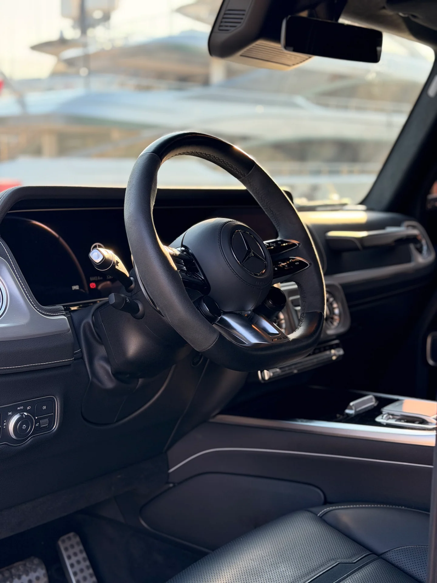 Dark Mercedes-AMG G63 cabin with steering wheel, dashboard and front seat