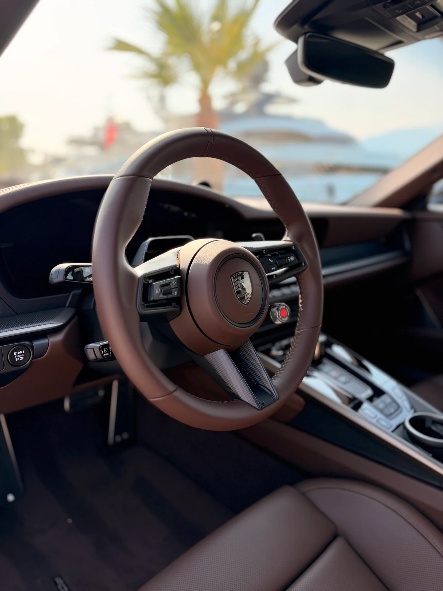 Brown Porsche 911 Turbo S cabin with steering wheel, front seat and centre console.